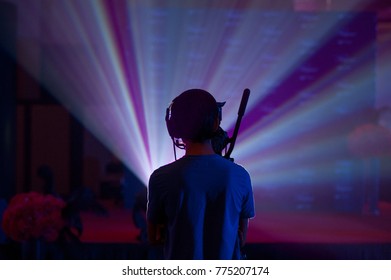 Silhouette Of A Cameraman Handling A Live Feed Camera With Ray Of Light In The Background.