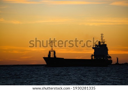 a silhouette of a cargo ship at sunset.