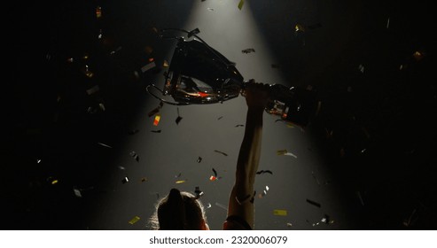 Silhouette of Caucasian woman female soccer football player raising a trophy above head against bright light and falling confetti. Super slow motion, shot on RED cinema camera - Powered by Shutterstock