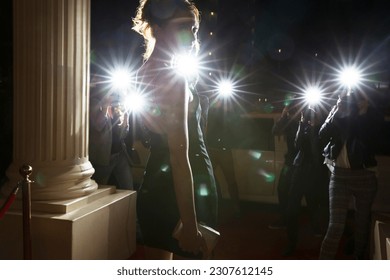 Silhouette of celebrity being photographed by paparazzi photographers at event