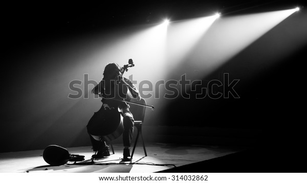 Silhouette cello player perform on stage with\
spotlight in monochrome,noise\
added