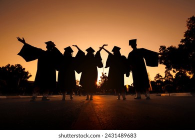 silhouette cheerful graduates group in black gowns Graduation at sunset - Powered by Shutterstock