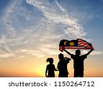 Silhouette of children waving the national flag in conjunction with Malaysia Independence Day. Selective focus. 