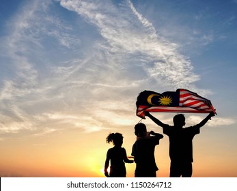 Silhouette of children waving the national flag in conjunction with Malaysia Independence Day. Selective focus. 