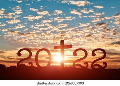 Silhouette of Christian cross with 2022 years at sunset background. Concept of Christians new year 2022