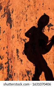 Silhouette Of Climber On Red Rock Face  