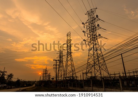 Silhouette of columns and high voltage wires In the power supply station There is a sunset background.