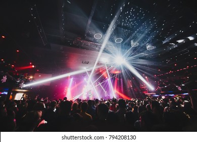 Silhouette Of Concert Crowd In Front Of Bright Stage Lights. Dark Background, Smoke, Concert  Spotlights, Disco Ball