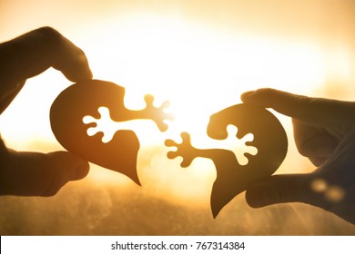 Silhouette Connect Heart Two Pieces Of Puzzle In Hands Of Lovers Against The Background Of Sunrise. Valentine's Day,