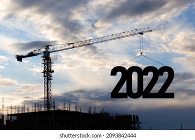 Silhouette of a construction crane at a construction site raising the number 2022 year. Concept for New Year 2022 for development and business - Shutterstock ID 2093842444