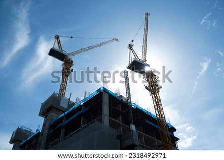 Silhouette Construction site background. Hoisting cranes and new multi-storey buildings. Industrial background. Building construction site work against blue sky.
