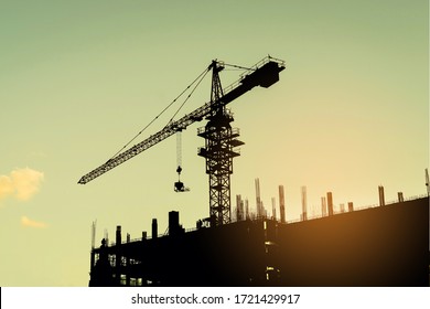 Silhouette of construction site including several cranes working on a building complex, with Light fair.