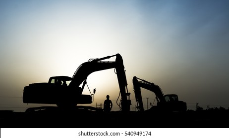 silhouette of a construction worker and  excavator in oilfield. 