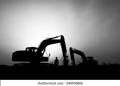 silhouette of a construction worker and  excavator in oilfield - black and white