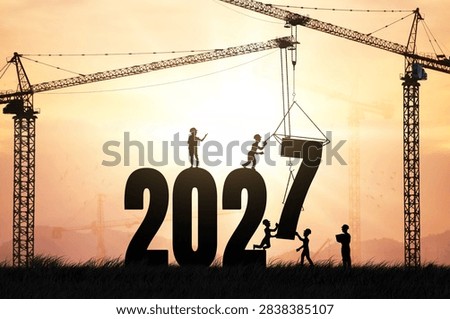Silhouette of construction workers and crane assembling giant 2027 numbers at golden sunset, representing teamwork, building future and industrial development