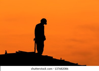 Silhouette Of Construction Workers On Scaffold Working Under A Hot Sun