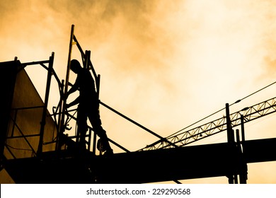 Silhouette Of Construction Workers On Scaffold Working Under A Hot Sun