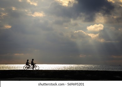 Silhouette of a couple enjoy their romantic riding at majestic sunset moment by the beach.