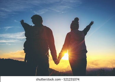 Silhouette of couple holding hands at sunset romantic concept