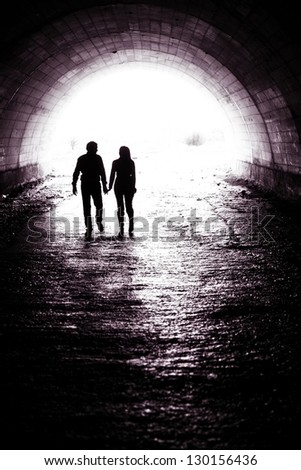 Silhouette of a couple holding hands and walking together in darkness