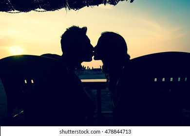 Silhouette Of Couple Kissing While Sitting On A Shack By The Beach At Sunset In Goa, India. Hippie Style, Honeymoon, Summer Vacation Destination, Love Concept. Vintage Effect