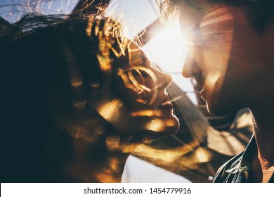 Silhouette of a couple. Couple in love silhouette during sunset - touching noses. Girl with flying hair. Sunshine on background
