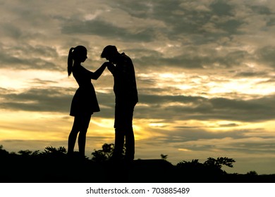 Silhouette couple in love Men ask for married and kissing at the hands of women on beautiful sunset background , valentine concept - Shutterstock ID 703885489