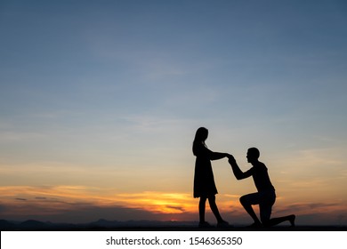 Silhouette Couple Man Down On One Knee Proposing To Woman Under Sunset Sky Background