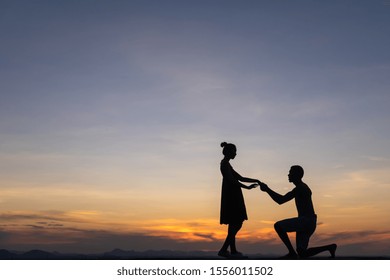 Silhouette Couple Man Down On One Knee Proposing To Woman Under Sunset Sky Background