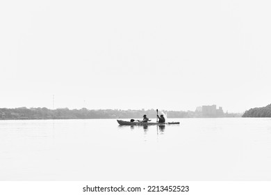 Silhouette Of Couple - Man And Woman Kayaking In The River At Sunset. Classical Black And White Photography Of High Contrast Scene.