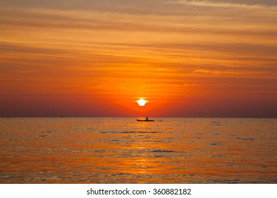 Silhouette Couple On Kayak Paddle In The Sea On The Sunset Background.