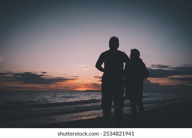 Silhouette of a couple standing on the beach at sunset, embracing and watching the horizon, capturing a peaceful and intimate moment. - Powered by Shutterstock