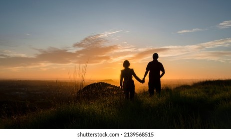 Silhouette couple standing on the hilltop looking at the sun rising over Auckland city. Photo taken at One Tree Hill.  - Powered by Shutterstock