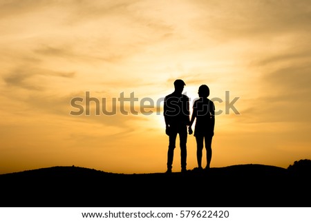 Silhouette Couple standing on a mountain sunset.