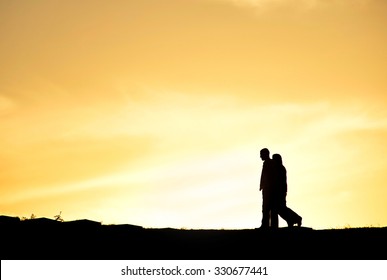 SIlhouette Of A Couple Walking At Sunset On A Hill