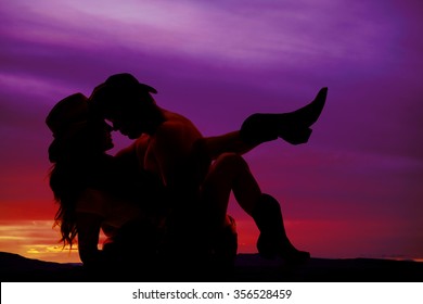 a silhouette of a cowboy holding on to his cowgirl.