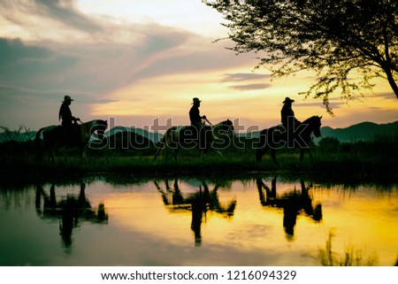 Silhouette the cowboy riding on a mountain with an yellow sky; Concept of friendly and of summer vacation.