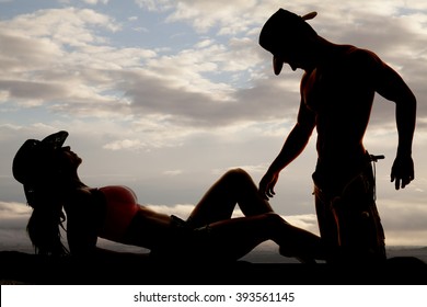 a silhouette of a cowgirl laying back with her cowboy touching her leg with his hand.
