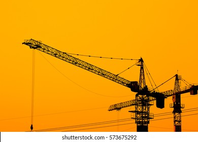 Silhouette of cranes construct building at orange sunset 