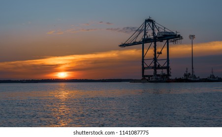 Silhouette of cranes during a beautiful golden sunset at a shipping port - Shutterstock ID 1141087775