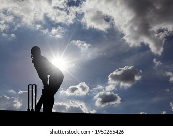 Silhouette Of A Cricket Batter Sportsman At The Wicket Stump On A Sunny Summer Day.