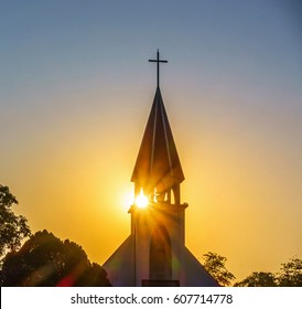 The silhouette of the cross and church bell tower in sunrise
