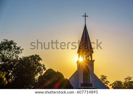 The silhouette of the cross and church bell tower in sunrise