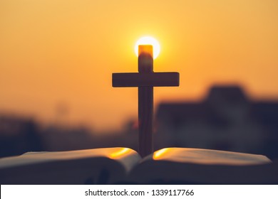 Silhouette of the cross  on the holy bible, religion symbol in light and landscape over a sunrise, background, religious, faith concept