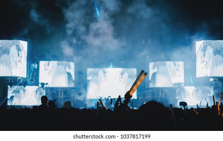 Silhouette Crowd Of Concert Stage Lights And People Fan Audience Raising Hands Or Glow Stick In The Music Festival Rear View 