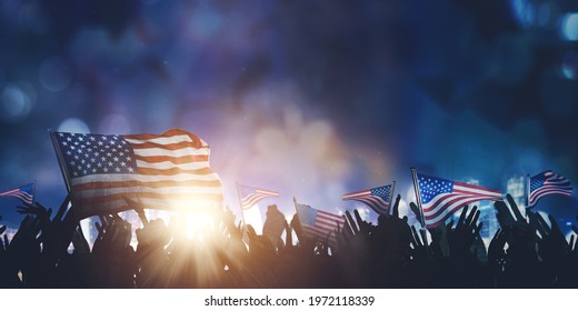 Silhouette of crowded people hands holding American flags while celebrating Independence Day with blurred sparkling light background. Shot at night time - Powered by Shutterstock