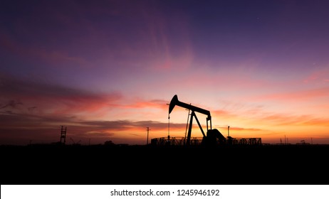 Silhouette of crude oil pump in the oilfield at sunset