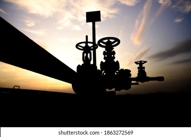 Silhouette of crude oil well control valve in the oilfield at sunset