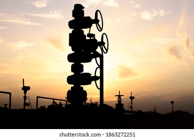 Silhouette Of A Crude Oil Well Head In The Oilfield At Sunset