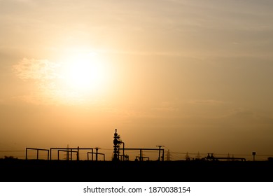 Silhouette Of A Crude Oil Well Head In The Oilfield At Sunset